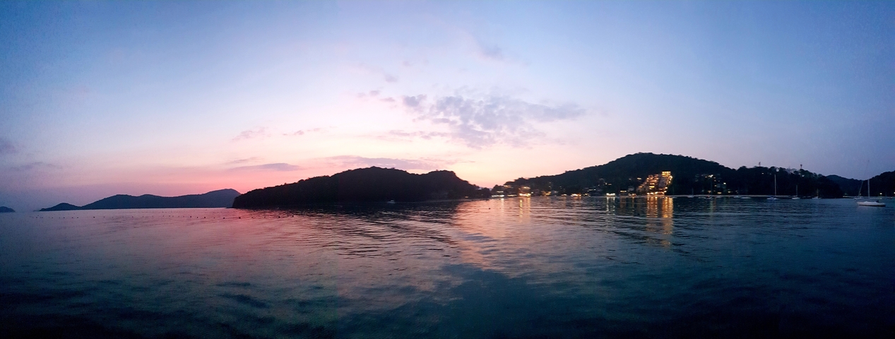 A sunset scene over water with a silhouetted coastline.