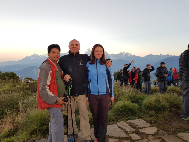       Three people posing with snowy mountains in the background.
  
