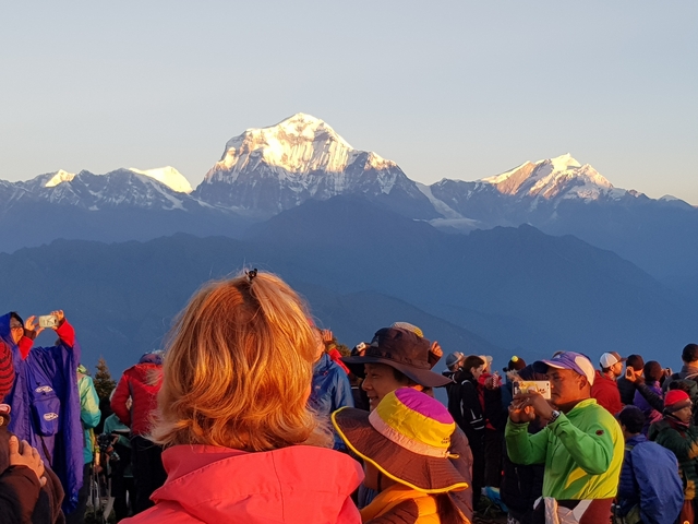 People gathered with mountains in the background, some taking pictures.