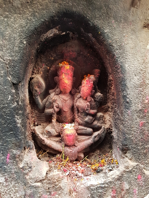A carved stone sculpture with red powder on it.