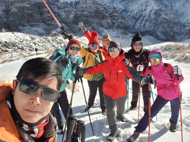       Group of skiers posing on a snowy mountain.
  