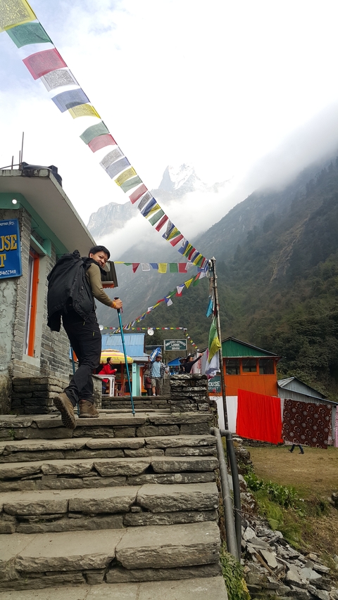 Hiker posing with trekking poles near colorful buildings.