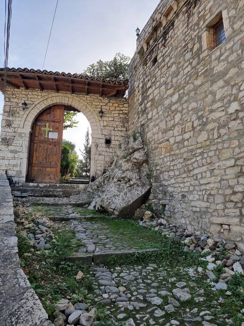 Archway entrance with stone walls and cobblestone path.