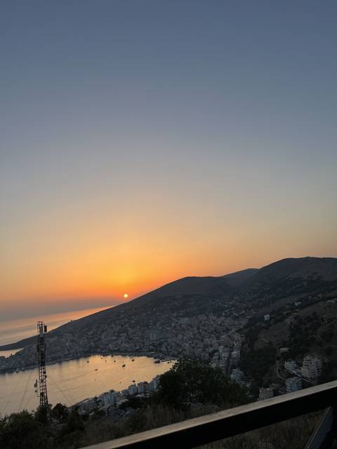 Sunset over a bay with buildings on a hillside.