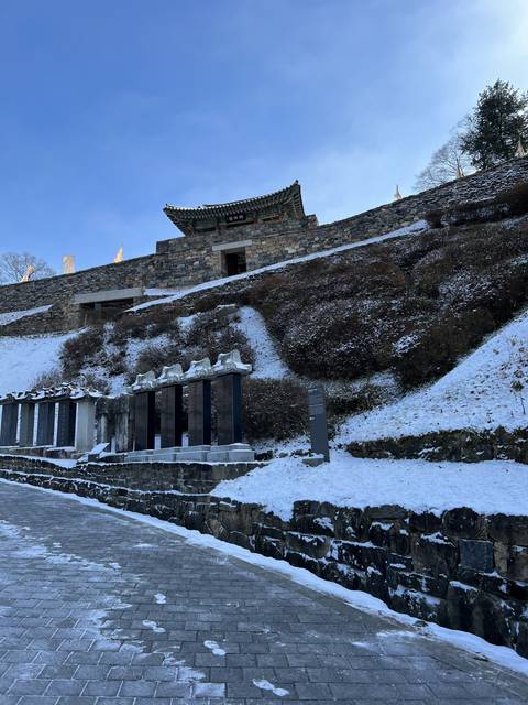       Stone wall and snow-covered building with stairs.
  