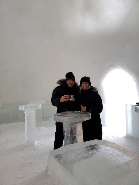       Couple in an igloo holding drinks.
  