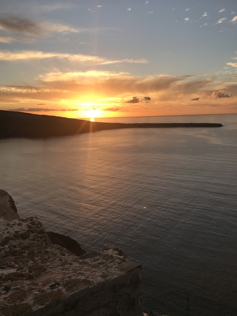 Sunset over a calm sea with a dark silhouette of land