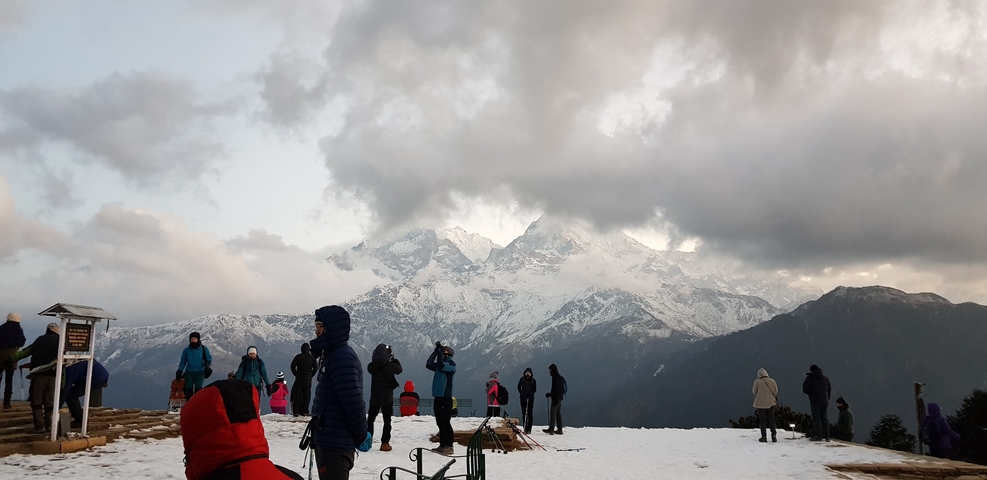       People enjoying a snowy mountain view with clouds.
  