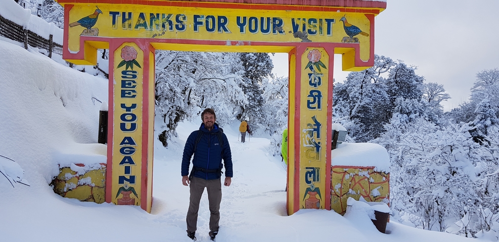       Person standing under a sign in a snowy landscape.
  