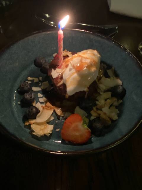 Dessert with berries, cream, and a lit candle on top.