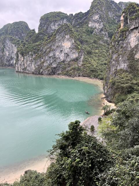       Aerial view of a bay with a beach and green hills.
  