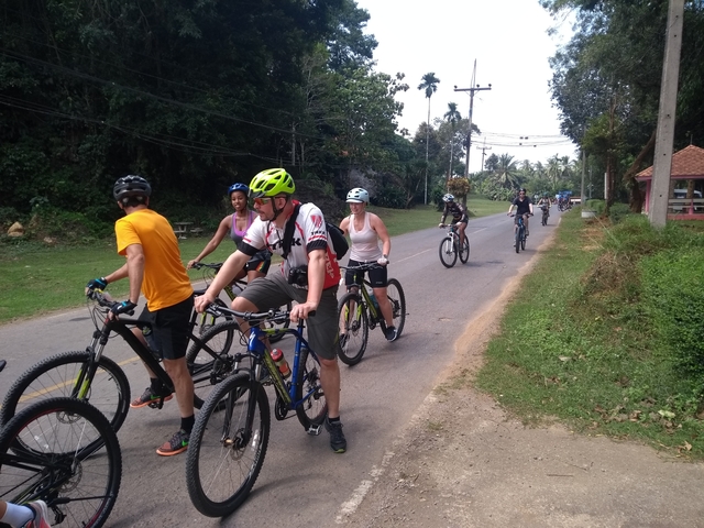 Group of people cycling down a rural road.