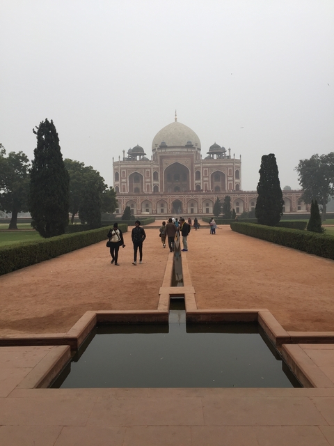       Mausoleum with gardens and people walking.
  