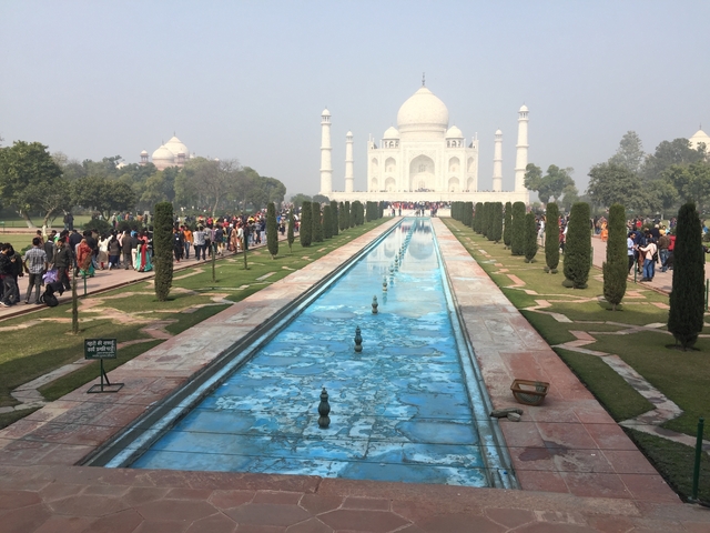       Iconic white marble mausoleum with gardens and visitors.
  
