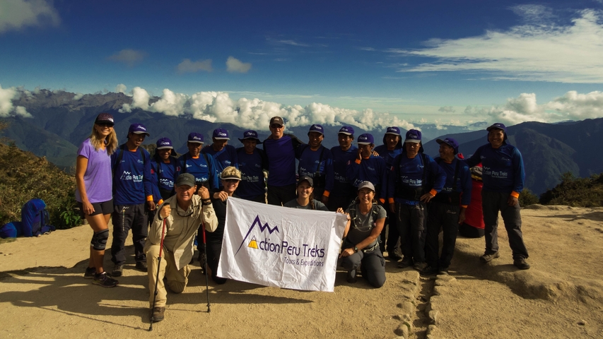      Hiking group holding a banner with mountains in the background.
  