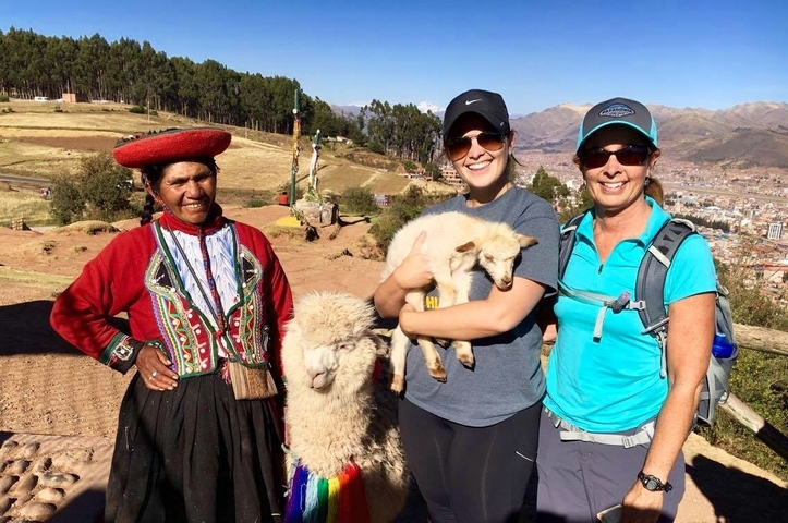       Three people with alpacas in a rural setting.
  