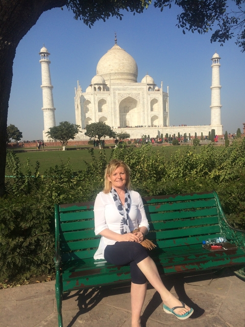Woman sitting on a bench in front of the Taj Mahal.
