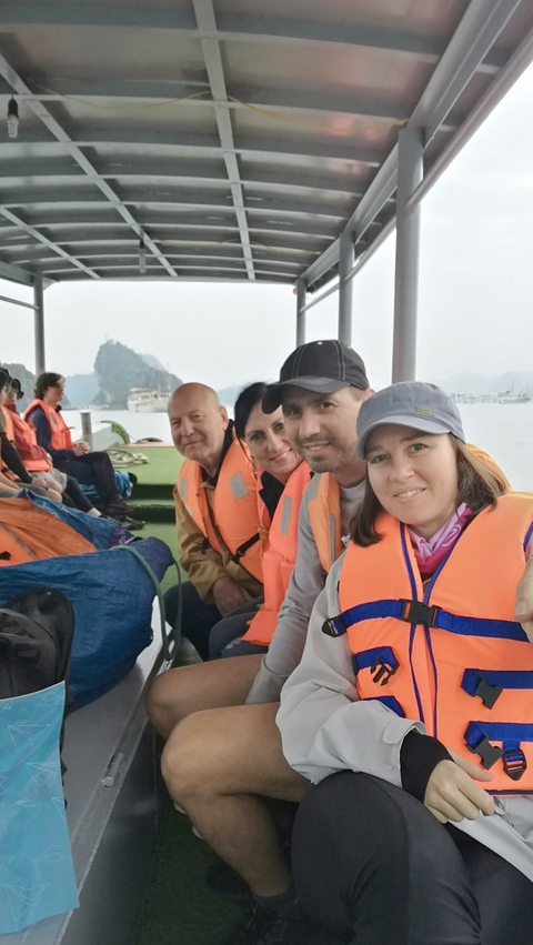       People seated on a boat wearing life jackets in a bay.
  