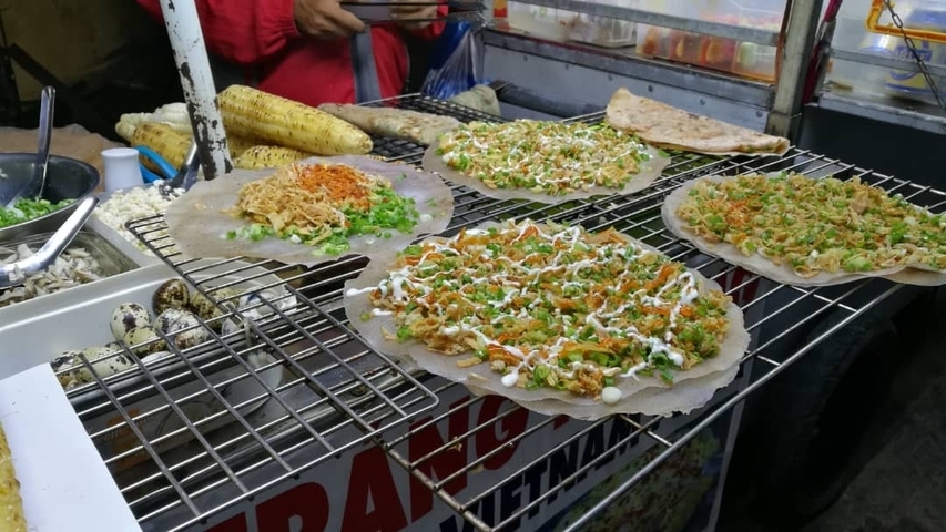       Street food setup with various dishes being prepared.
  
