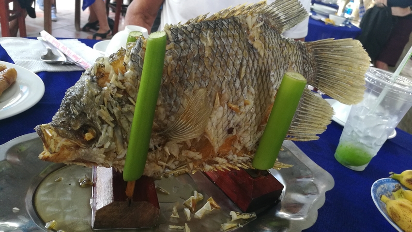       A whole cooked fish on a platter with decorative presentation.
  