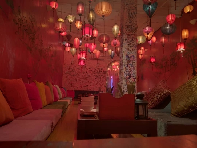 Interior of a cafe with colorful lanterns and cushioned seating.