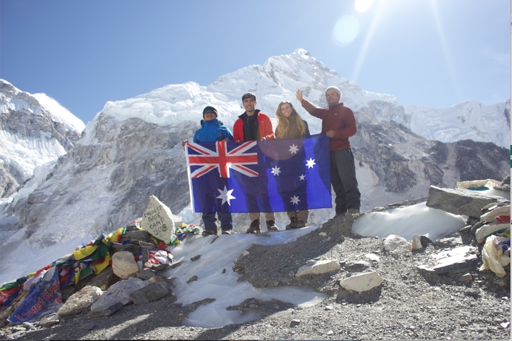 Group holding a flag in front of snowy mountains.