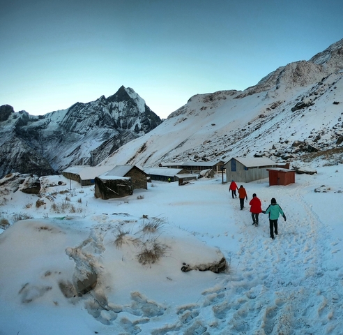       Hikers walking through a snowy mountain village.
  