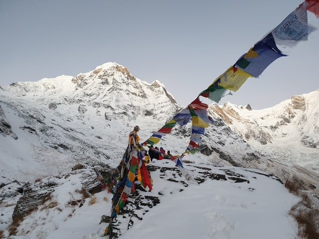      Snow-covered mountain landscape with colorful prayer flags.
  