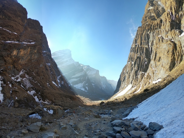 Mountain gorge with snow and sunlight streaming through.