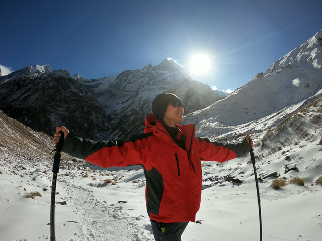       Hiker posing with trekking poles in snowy mountains.
  