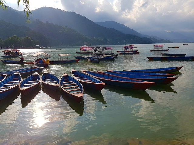       Boats on a calm lake with mountains in the background.
  