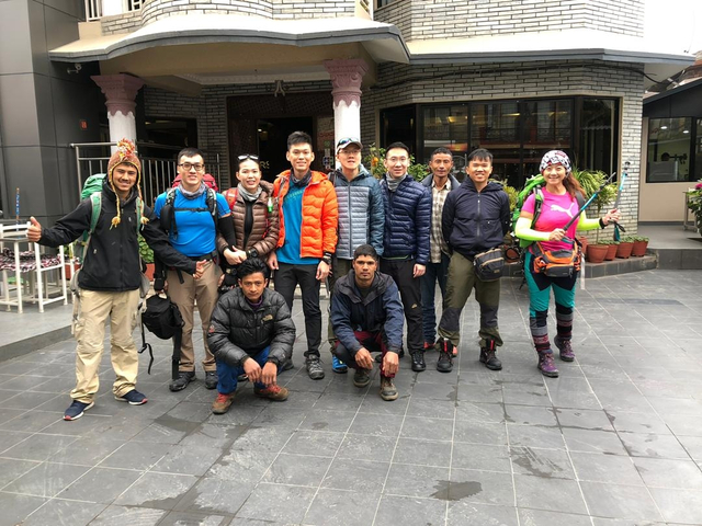 Group of trekkers with backpacks outside a building.