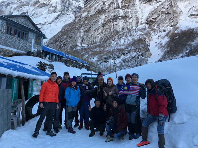 Group of trekkers posing in front of snowy mountains.
