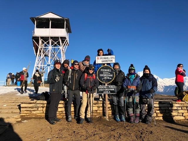 Group of hikers with signpost at Poon Hill in the snow.