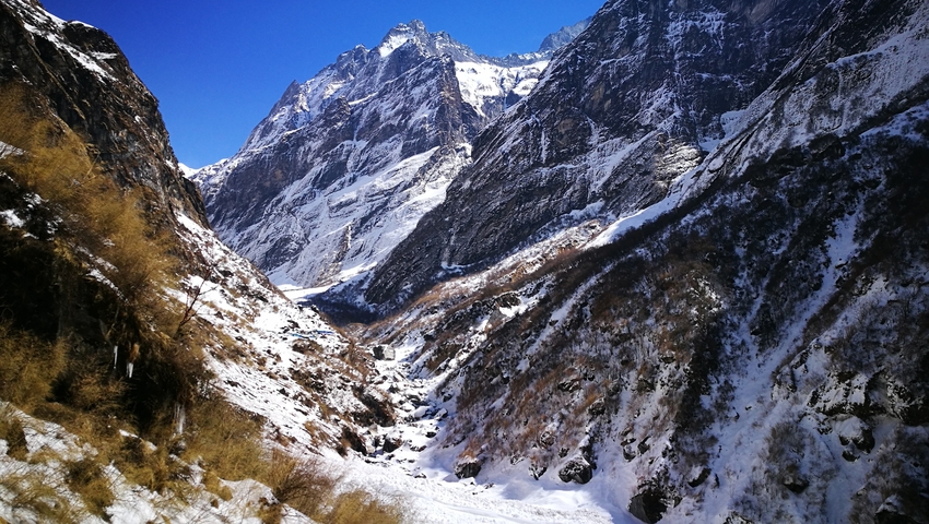 Snow-covered mountain range under a bright blue sky.