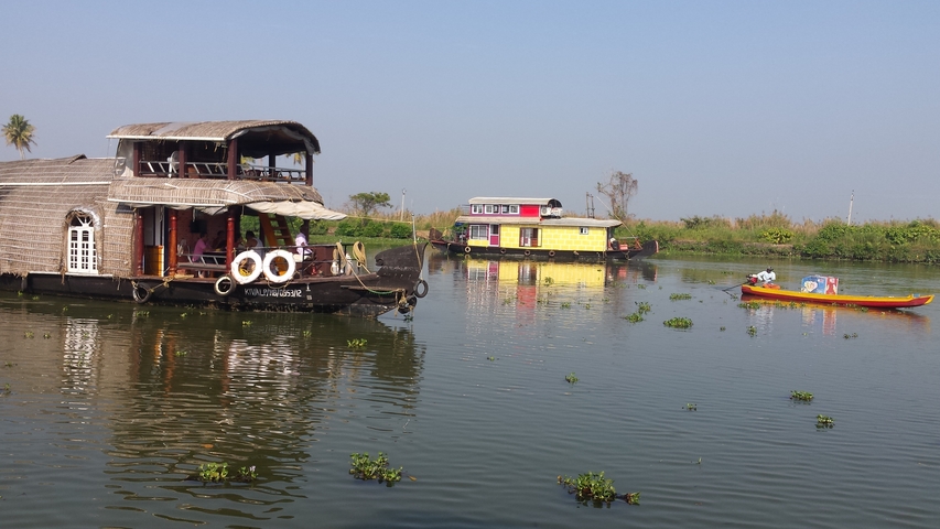       Houseboats on a calm river with small boats.
  