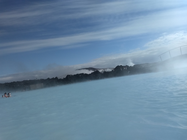 People relaxing in a geothermal pool with steam.