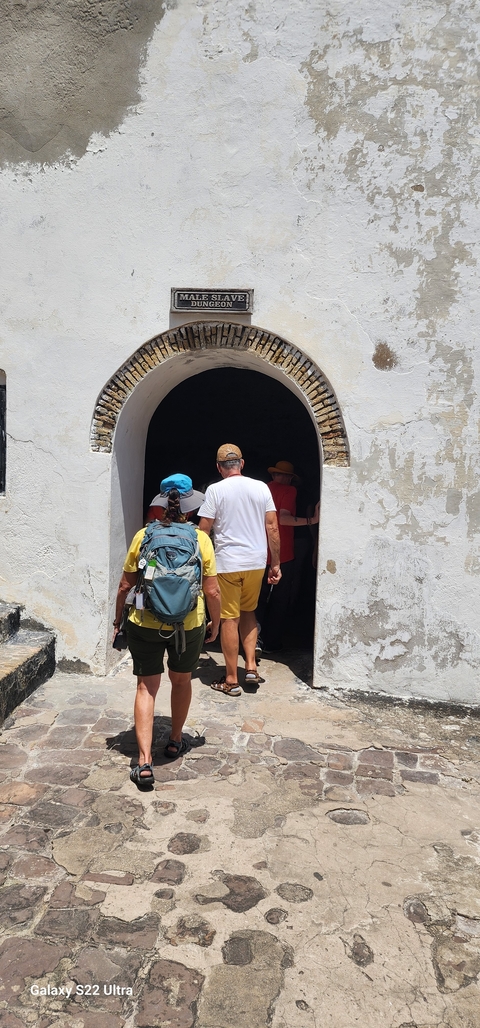 People walking through a historical arched entrance.