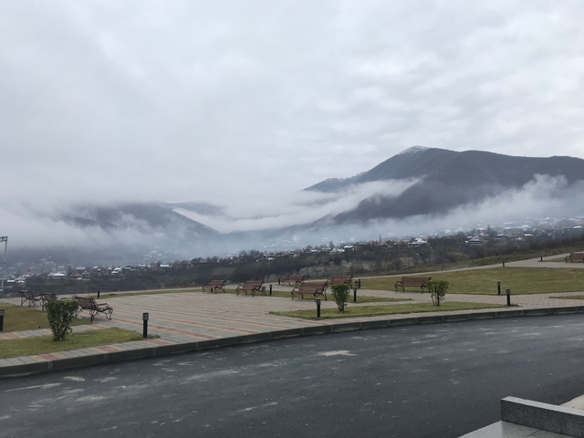       Mountainous landscape with benches and clouds.
  