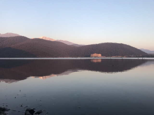 Lake with a distant building surrounded by hills.