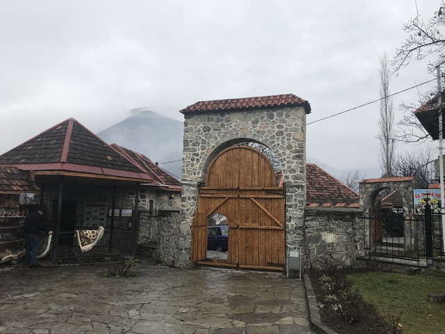       Stone arch and buildings with a mountain in the background.
  