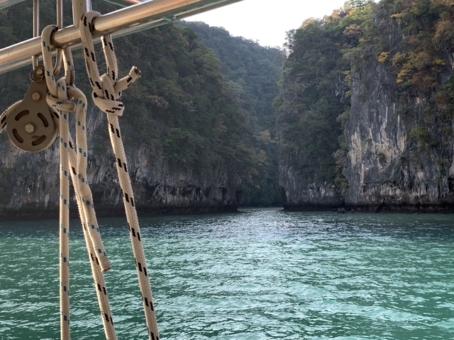 A boat sailing through a narrow passage between limestone cliffs.