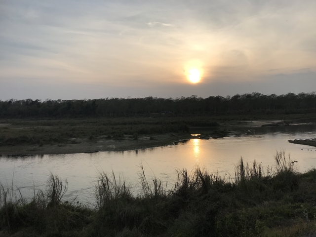       Sunset over a river with forested banks.
  