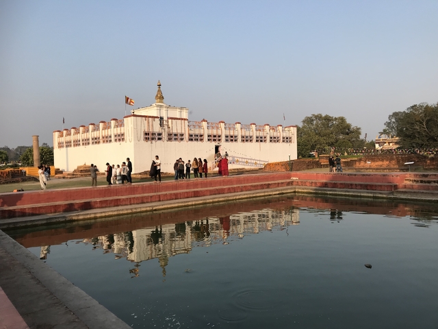 Group of people at a historic site with reflective pool.