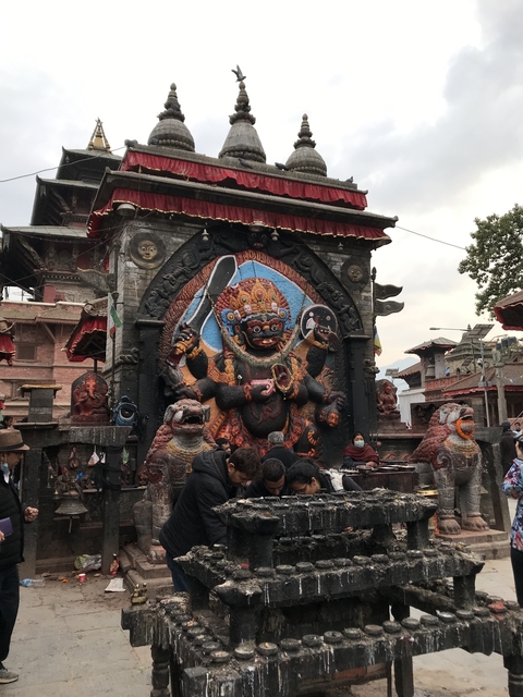 Vibrant Hindu temple with intricate deity sculpture and visitors.