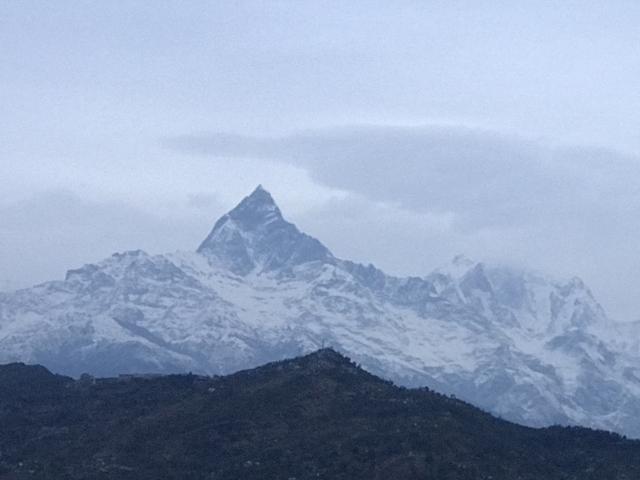 Snowy mountain range under a cloudy sky.