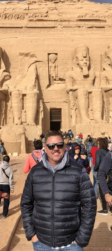       A group of tourists at a historical Egyptian site with colossal statues.
  
