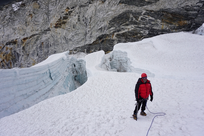       A climber standing on a snowy field with ice formations.
  