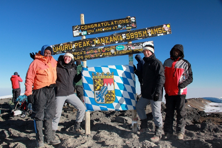       Group photo at Uhuru Peak with a flag
  