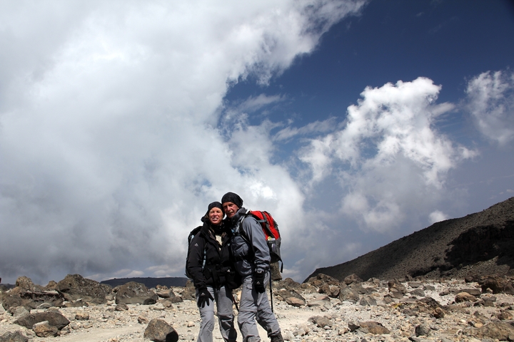Two hikers embracing with a dramatic sky in the background.